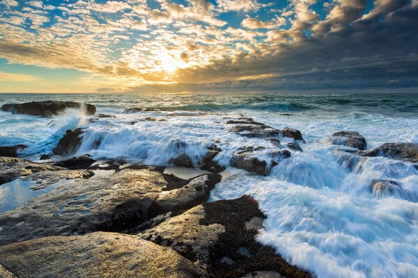 The sun breaking through the clouds on the fore of the sea