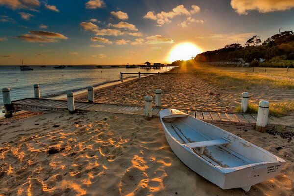 Sunset lights up a boat on a sandy beach