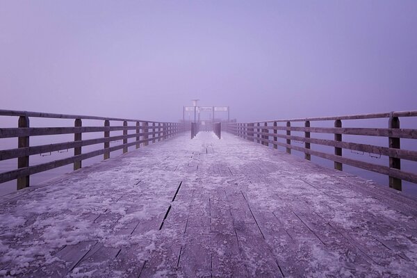 Der Fliedernebel fiel auf eine mit Schnee bedeckte Holzbrücke