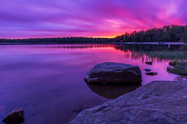 Lilac dawn. Rocks on the lake