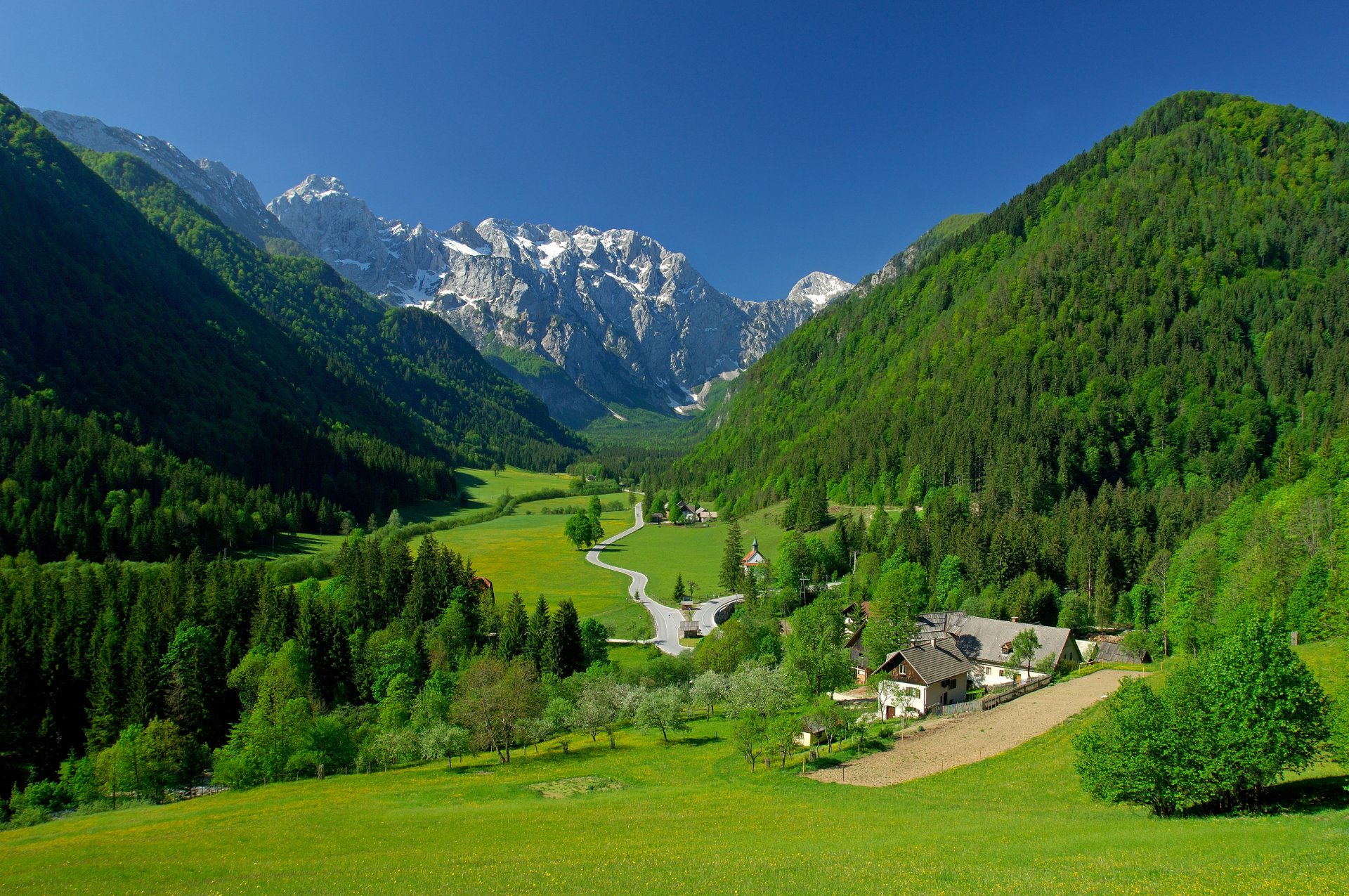 frühling berge alpen tal häuser bäume gras grüns himmel