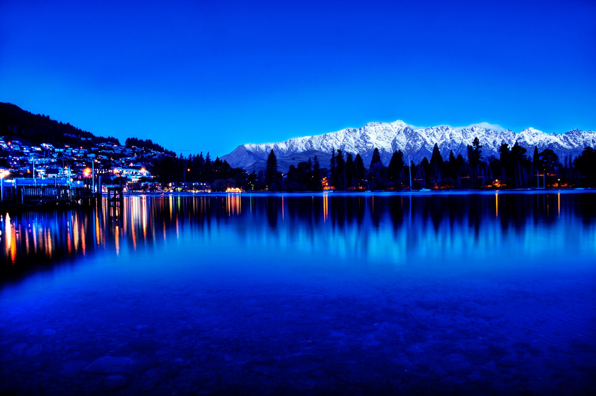 montañas pinos lago ciudad crepúsculo luces reflexión