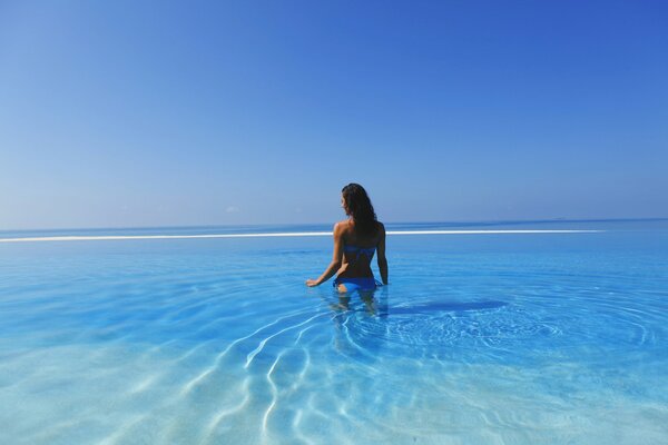 Ragazza in costume da bagno blu che sta nell acqua