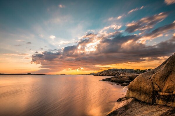 The rays of the rising sun are reflected in the calm waters of the sea