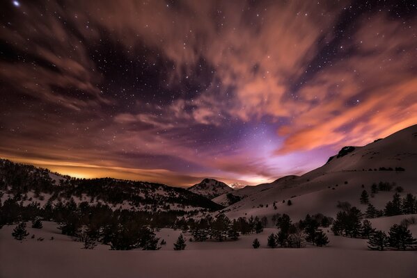 Resplandor sobre las montañas nevadas por la noche