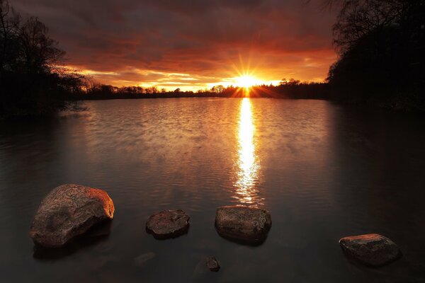 Amanecer por la mañana sobre el lago con piedras