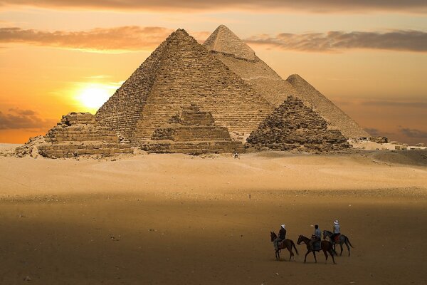 Image of a bright yellow pyramid on the background of sunset, riders in the desert