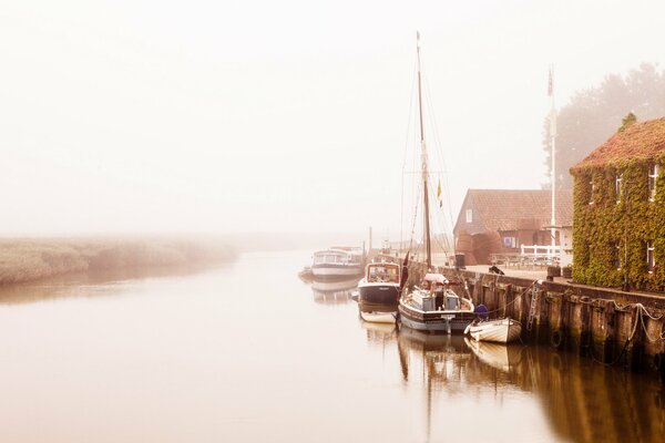 Mooring with boats on the river bank in the fog