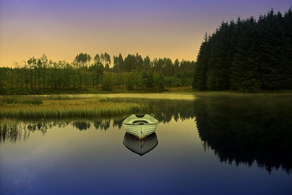 Reflejo del barco en el lago. Amanecer en el bosque