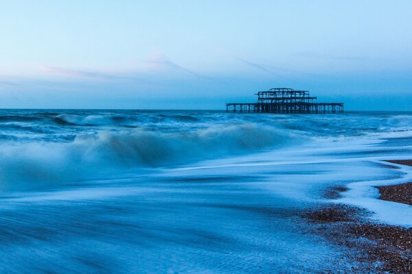 Plage de pierre, ciel bleu et vagues qui font rage