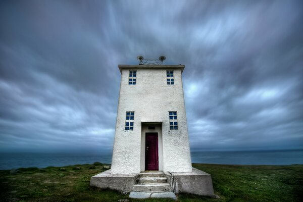 Leuchtturm in Island, vor dem Hintergrund eines dunklen Himmels mit Wolken und einer Wüstenlandschaft