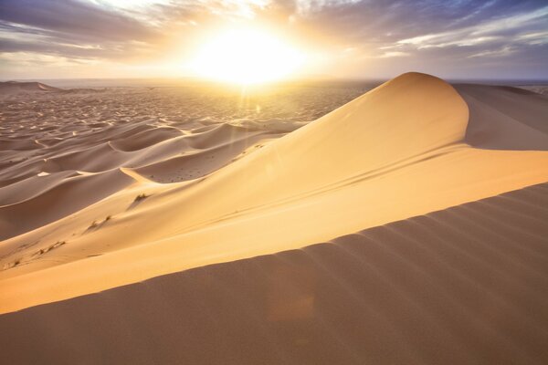 The sun illuminates the dunes of the Moroccan desert