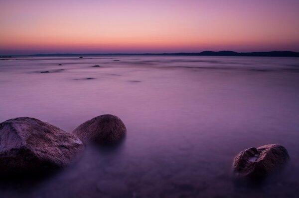 Tramonto lilla sul mare con pietre