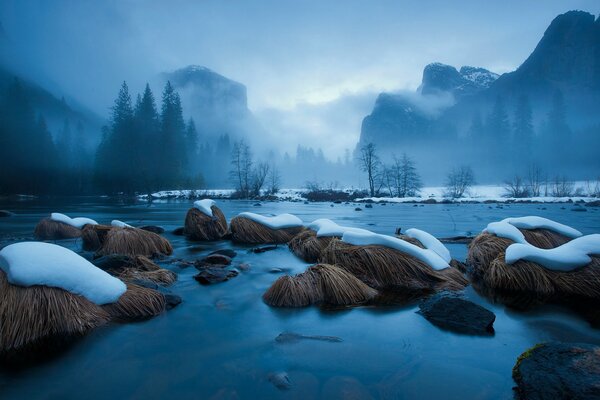 Stones with snow on the water in the mountains