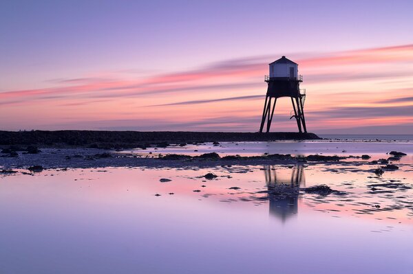 Faro en el Reino Unido en la orilla del mar al amanecer