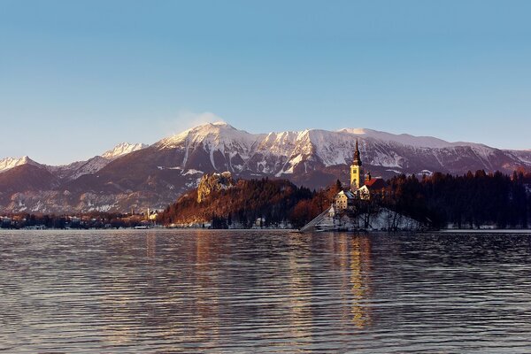 Das Schloss ist von Bergen und Wald umgeben, auf dem Hintergrund der Wasseroberfläche des Sees