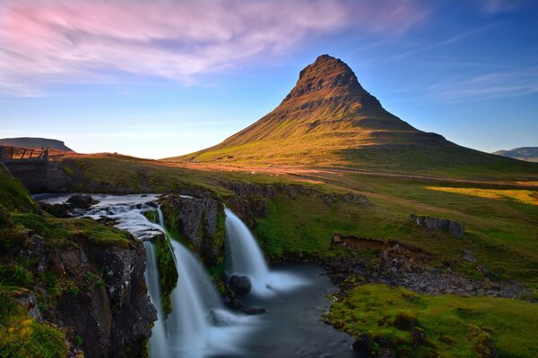 Водопад kirkjufellsfoss в Исландии на фоне пустынного скалистого пейзажа