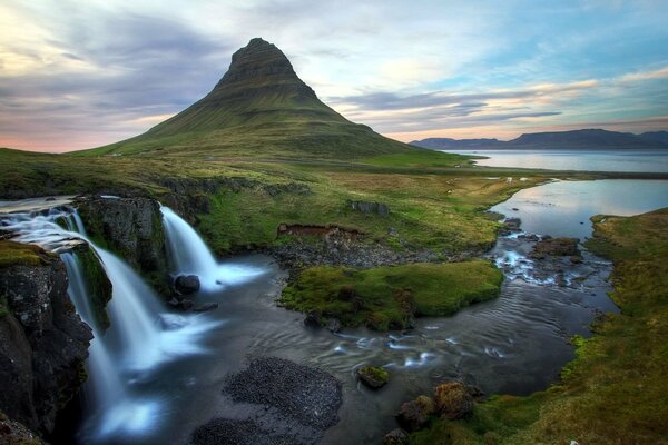 Waterfall with lake and mountain covered with greenery