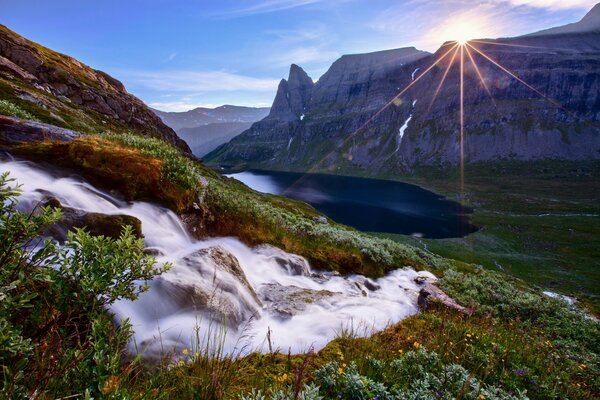 El sol aparece sobre las montañas y el lago