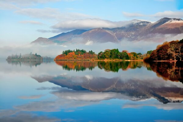 A lake with clouds reflected in it on the background of an autumn forest