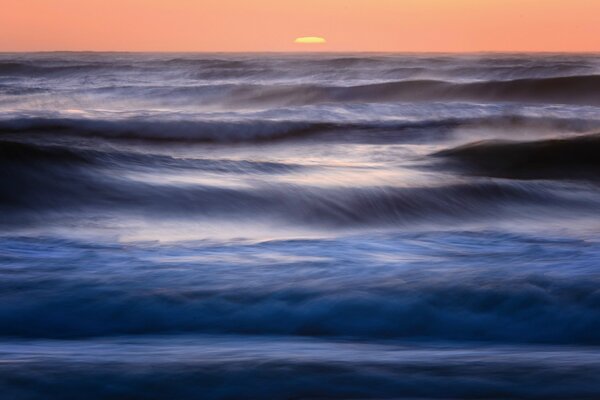 Olas del mar y el sol que se pone en el horizonte