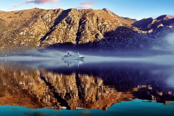 Barco en la superficie del agua en el fondo de las montañas de otoño