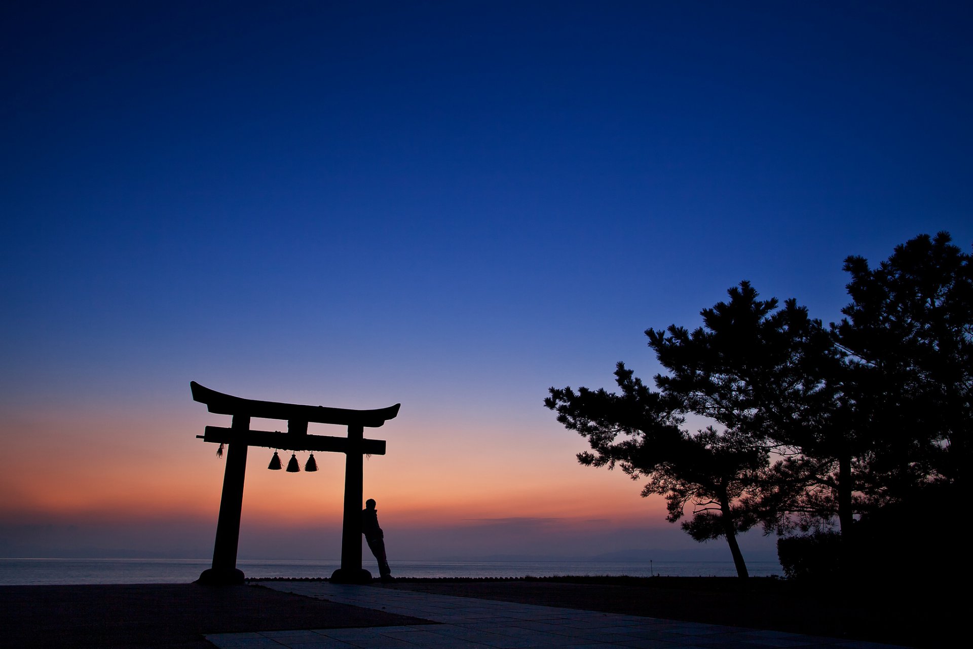 japan abend orange sonnenuntergang blau himmel bäume torii architektur mann silhouette