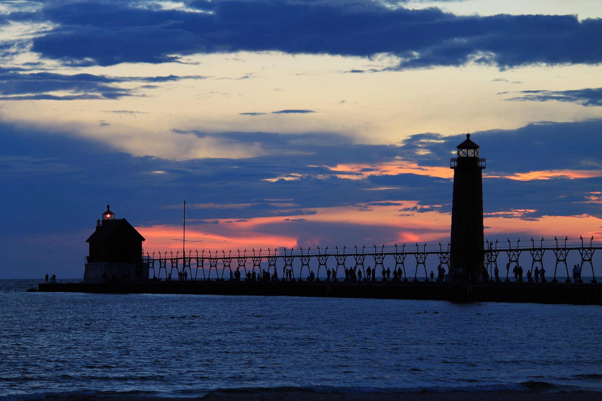 evening orange sunset sky clouds sea lighthouse light pier pier people