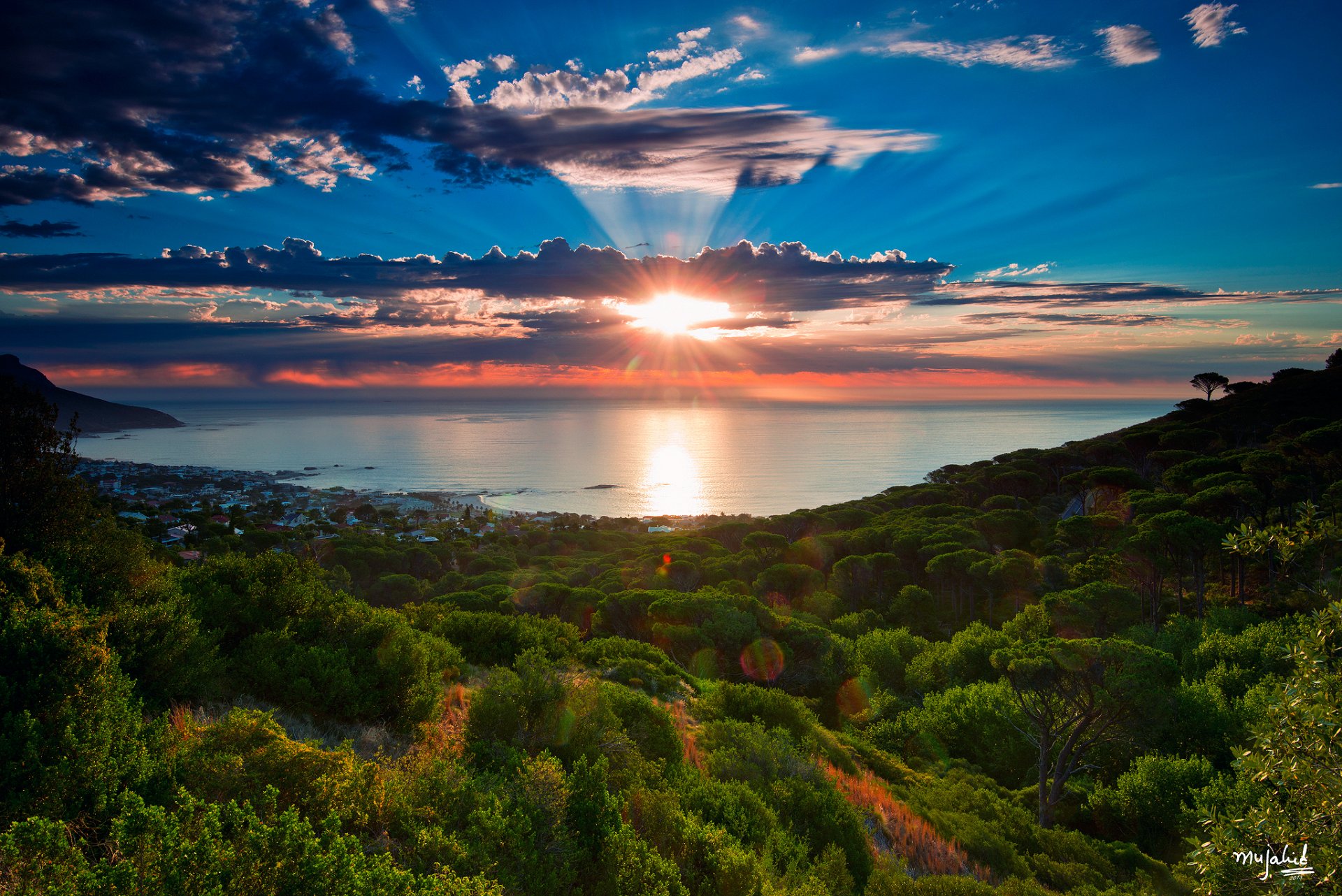 sudáfrica ciudad del cabo camps bay océano atlántico bahía mar océano árboles invierno enero cielo nubes sol rayos mujahid ur-rehman fotografía