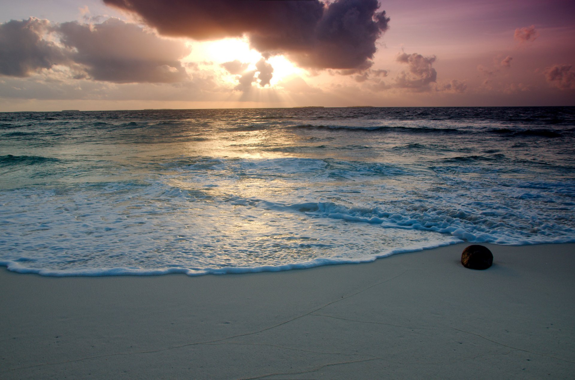 ea water foam beach sand stone sky clouds sun