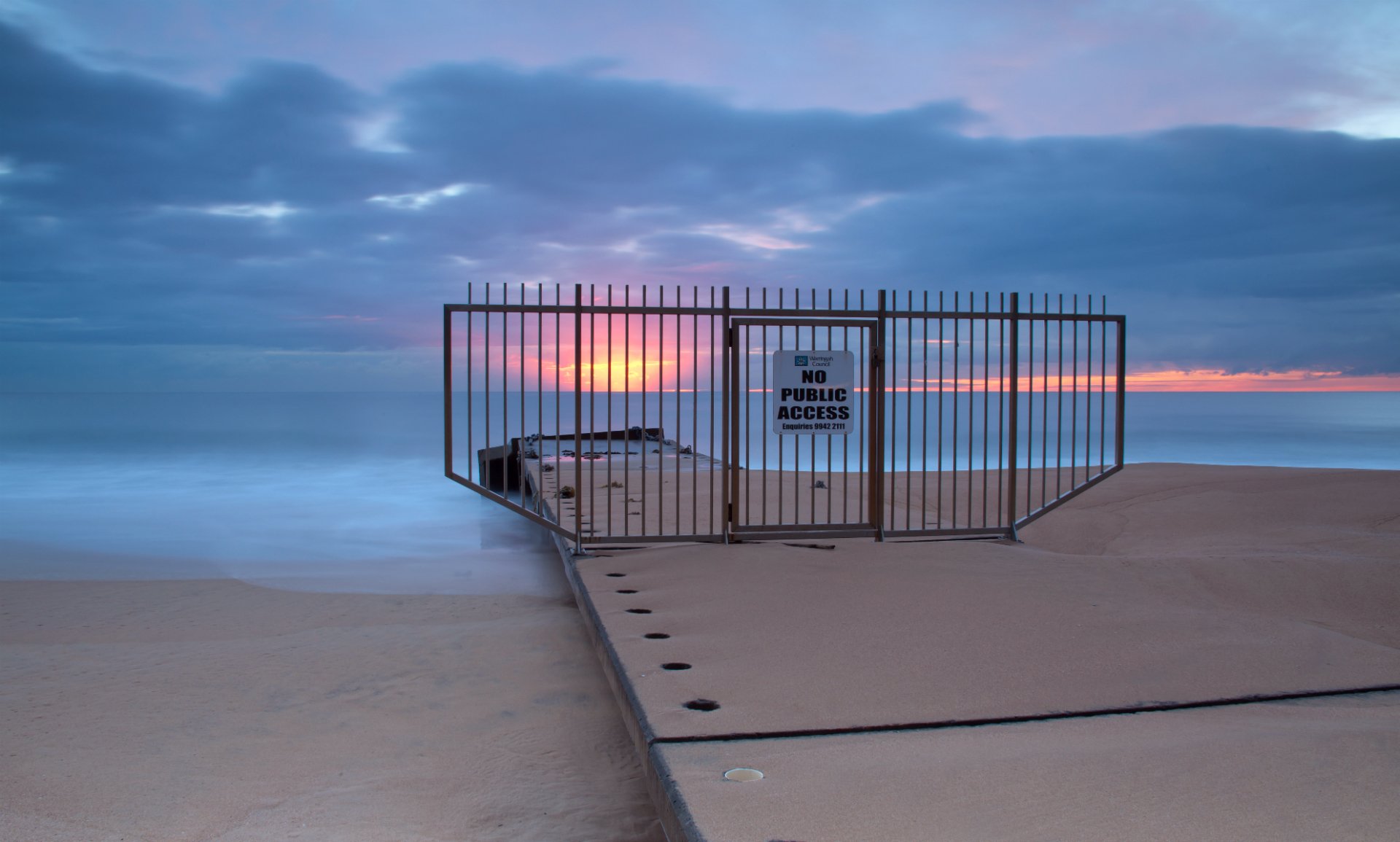 night sunset sun sky clouds sea ocean calm beach sand fencing