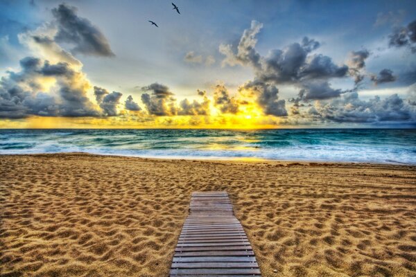 Ein Sandstrand am Horizont, ein Feuer der Sonnenuntergangssonne und Bleiwolken