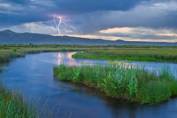 Relámpago en las montañas en el fondo del río