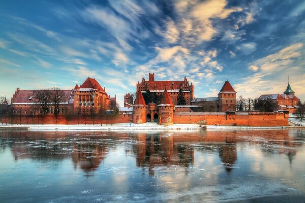 Schloss in Polen im Winter neben einem eisigen See in Reflexion