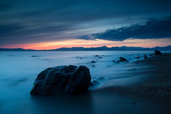 Coucher de soleil sur la mer. Plage vide avec des pierres