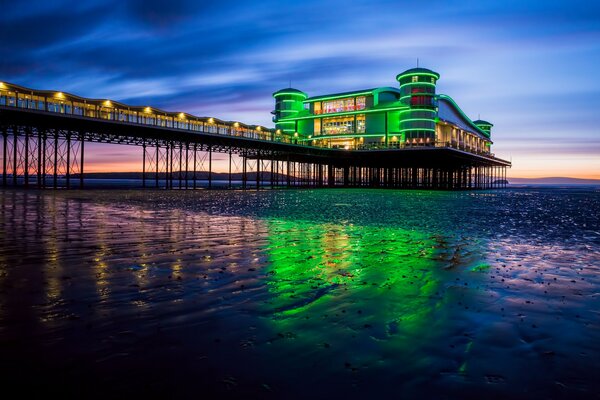 A luminous building on a pier by the sea