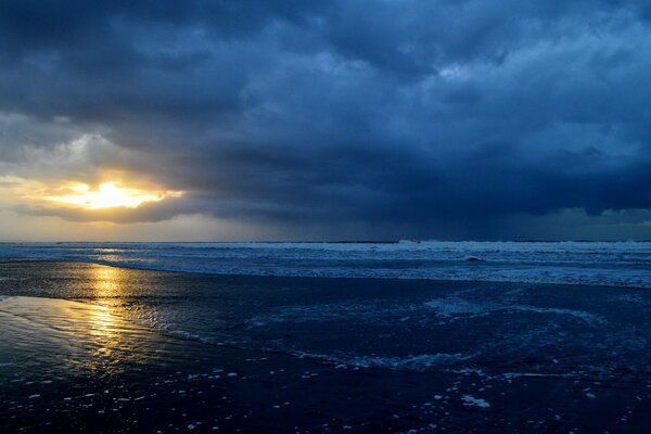 Dark gloomy clouds over the waves and a ray of sunshine through the clouds