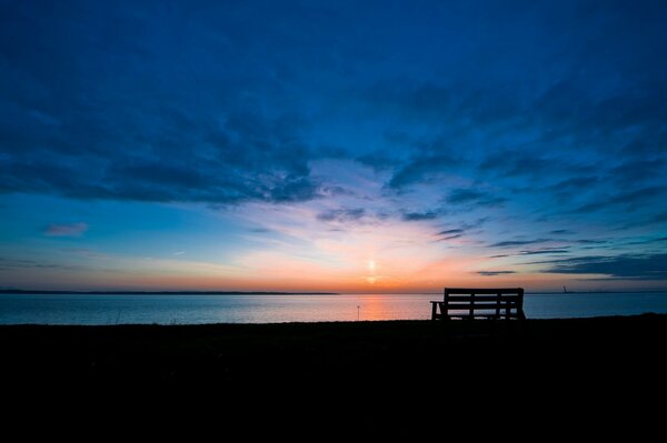 Landscape with a bench by the water at sunrise