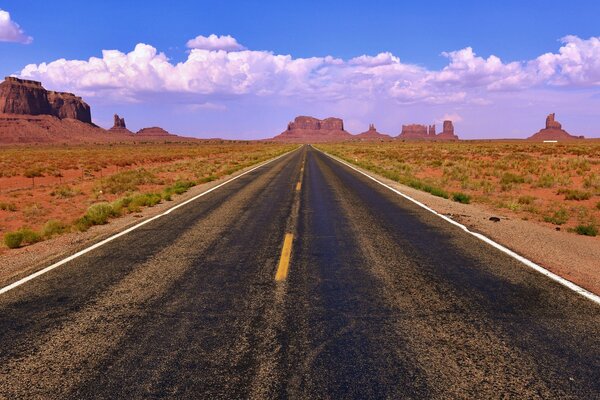 Der Weg, der an den Seiten der Landschaften von Ebenen und Felsen in die Ferne führt