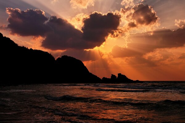 Die Sonnenstrahlen brechen durch die Wolken am Meer