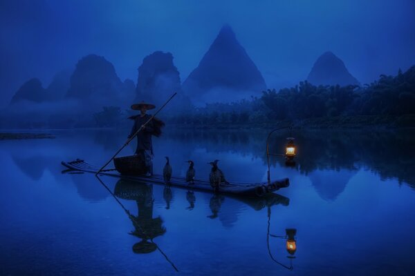 A fisherman catches fish in the morning in China on a boat under a lantern