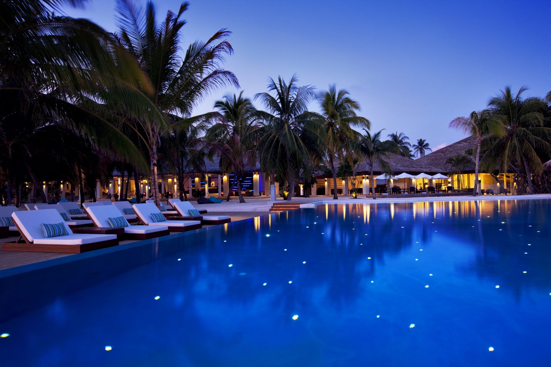 malediven hotel velassaru abend schwimmbad liegestühle bäume palmen