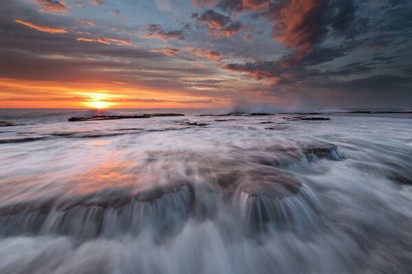 Streams of seething sea water at sunset