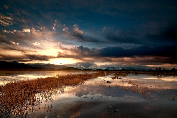 Thoughtful reflection of mountains and clouds in the mirror surface of the lake