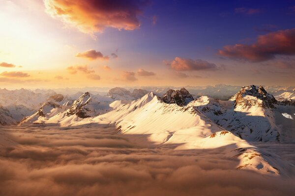 Die Gipfel der schneebedeckten Berge unter den Wolken