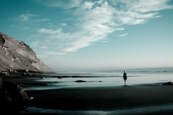 The coastal edge of the water and the girl looks at the mountains