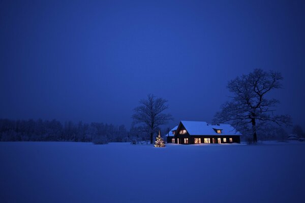 Casa de pie en un valle cubierto de nieve en la noche de Navidad