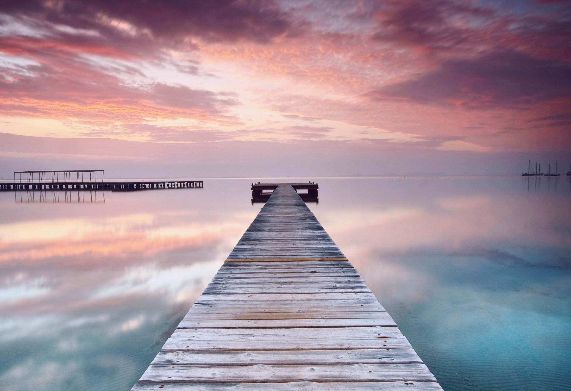 pain beach sea calm water smooth surface reflection wooden bridge bridge evening orange pink sunset sky cloud