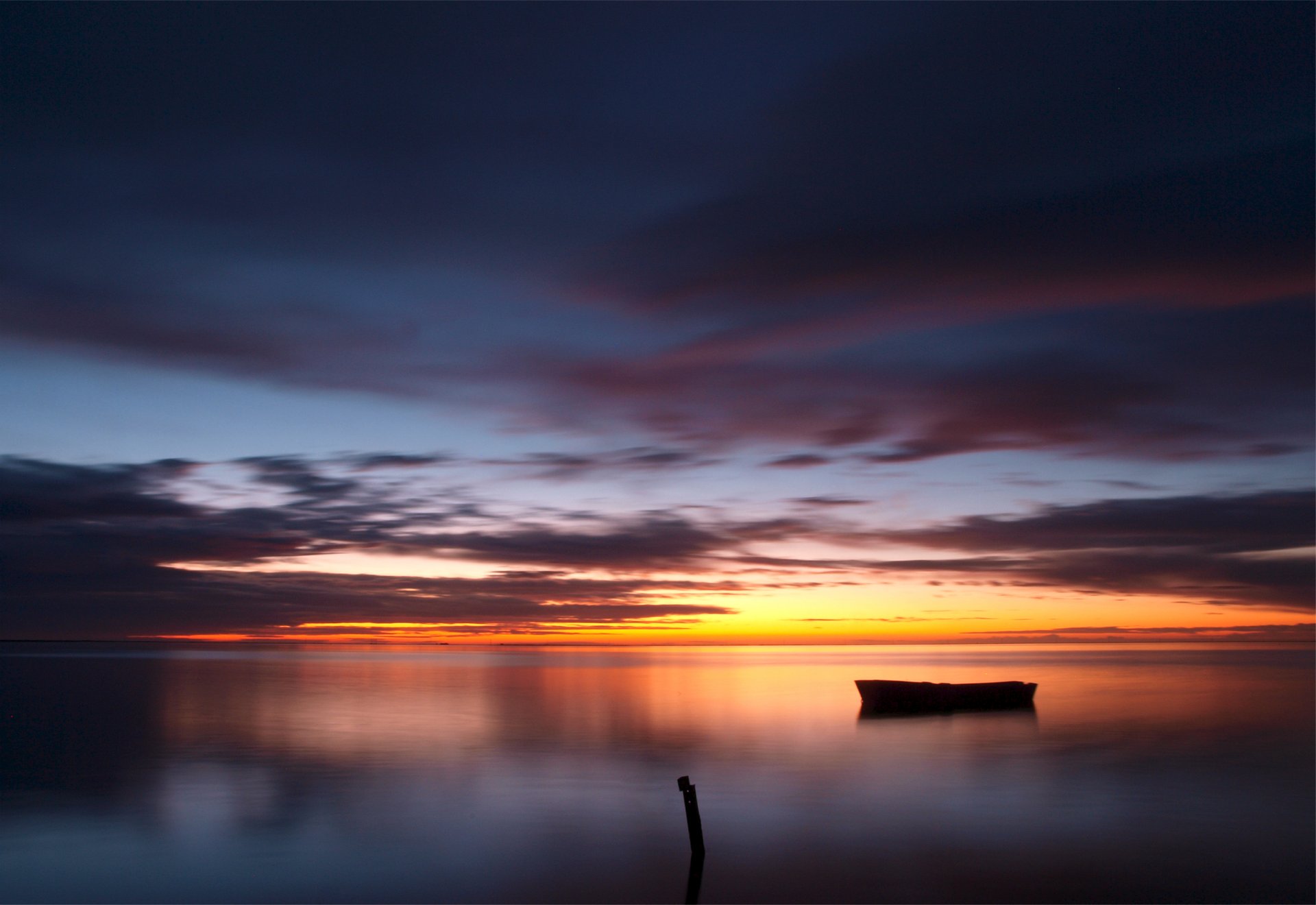 evening sunset sky clouds clouds lake water surface reflection boat wooden column