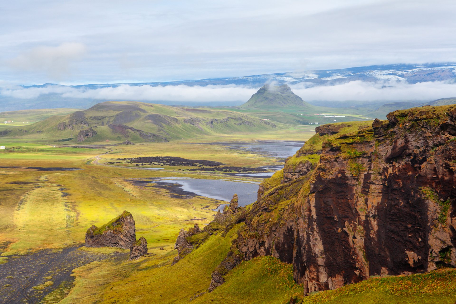 islandia góry skały zbocza trawa kwiaty niebo chmury